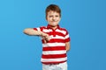 Little child boy in red striped shirt making disagree disapprove finger sign against blue background Royalty Free Stock Photo