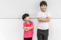 Little child boy standing arms crossed and looking face of tall child at standing arms crossed and smiling