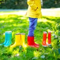 Little child in colorful rain boots. Close-up of school or preschool legs of kid boy or girl in different rubber boots