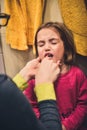 Little child is crying while mother brushes her teeth.