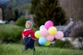 Little child, cute boy on a spring cold windy rainy day, holding colorful balloons in a field, running Royalty Free Stock Photo