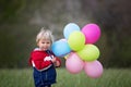 Little child, cute boy on a spring cold windy rainy day, holding colorful balloons in a field, running Royalty Free Stock Photo