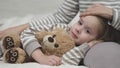 little child daughter lies her mother lap hugging teddy bear. time sleep kid. mom strokes cares girl daughter head. nice Royalty Free Stock Photo