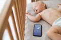 Little child napping in bed with phone playing lullaby in application for baby sleep in bedroom