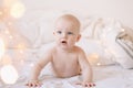 Little child doing tummy time. Adorable baby learning to crawl in white  bedroom. Cute funny baby lying on bed. Royalty Free Stock Photo
