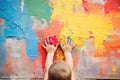 little child draws with his hands on the wall with bright multi-colored paints