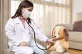 Little child dressed as a doctor examining a teddy bear with a stethoscope. Concept of health and wellness at home Royalty Free Stock Photo