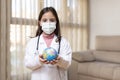 Little child dressed as a doctor with a medical mask holding a ball of the world in her hands. World Health Day concept Royalty Free Stock Photo