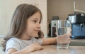 Little child is drinking clean water at home, close up. Caucasian cute girl with long hair is holding a water glass in her hand Royalty Free Stock Photo