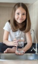 Little child is drinking clean water at home, close up. Caucasian cute girl with long hair is holding a water glass in her hands Royalty Free Stock Photo