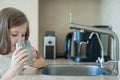 Little child is drinking fresh and pure tap water from glass. Water being poured into glass from kitchen tap. Zero waste and no Royalty Free Stock Photo