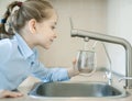 Little child is drinking fresh and pure tap water from glass. Water being poured into glass from kitchen tap. Zero waste and no Royalty Free Stock Photo