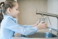 Little child is drinking fresh and pure tap water from glass. Water being poured into glass from kitchen tap. Zero waste and no Royalty Free Stock Photo