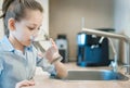 Little child is drinking fresh and pure tap water from glass. Water being poured into glass from kitchen tap. Zero waste and no