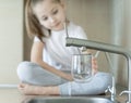 Little child is drinking fresh and pure tap water from glass. Water being poured into glass from kitchen tap. Zero waste and no Royalty Free Stock Photo