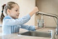 Little child is drinking fresh and pure tap water from glass. Water being poured into glass from kitchen tap. Zero waste and no Royalty Free Stock Photo