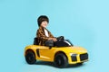 Little child driving yellow toy car on light blue background Royalty Free Stock Photo