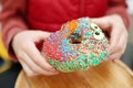 Little child eating funny colorful donut in a street cafe while walking in the city center Royalty Free Stock Photo