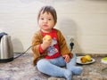 Little child eats a pear. child boy eating fruits at a high stoic. in the kitchen Royalty Free Stock Photo