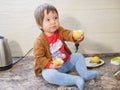 Little child eats a pear. child boy eating fruits at a high stoic. in the kitchen Royalty Free Stock Photo