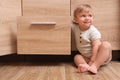 Little child exploring drawer indoors. Danger situation Royalty Free Stock Photo