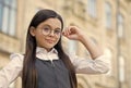 Little child fix round-framed eye glasses wearing formal school uniform outdoors, vision. formal education