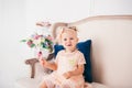 Little child girl in beautiful dress eats cake while sitting on sofa in living room. The princess in pink dress holds festive Royalty Free Stock Photo