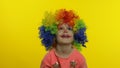 Little child girl clown in colorful wig making silly faces, having fun, smiling, dancing. Halloween Royalty Free Stock Photo