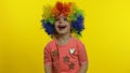 Little child girl clown in colorful wig making silly faces, having fun, smiling, dancing. Halloween Royalty Free Stock Photo
