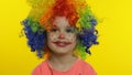 Little child girl clown in colorful wig making silly faces, having fun, smiling, dancing. Halloween Royalty Free Stock Photo