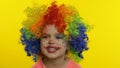 Little child girl clown in colorful wig making silly faces, having fun, smiling, dancing. Halloween Royalty Free Stock Photo