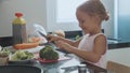 Little child girl cutting brocoli for cooking at domestic kitchen.