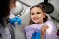 Little child girl in dentist's chair, smiles to her doctor during regular dental check-up in pediatric dentistry Royalty Free Stock Photo