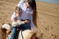 Little child girl feeling worried and hugging her mother while riding pony on the sandy beach Royalty Free Stock Photo