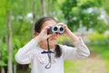 Little child girl in a field looking through binoculars in nature outdoor. Explore and adventure concept Royalty Free Stock Photo