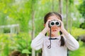 Little child girl in a field looking through binoculars in nature outdoor. Explore and adventure concept Royalty Free Stock Photo