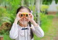 Little child girl in a field looking through binoculars in nature outdoor. Explore and adventure concept Royalty Free Stock Photo
