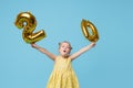 Little child girl is holding foil balloons in the form of numbers 20 twenty percent. The concept of discounts,