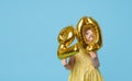 Little child girl is holding foil balloons in the form of numbers 20 twenty percent. The concept of discounts,