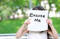 Little child girl holding up a white paper with write text Excuse Me in nature park