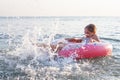 Little child girl laughing and crying in the splash of waves at sea on a sunny day