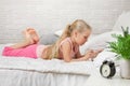 Little child girl lies in bed uses digital tablet. Royalty Free Stock Photo