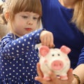 Little child girl with mom throws coins into piggy bank Royalty Free Stock Photo
