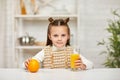 Little child girl with oranges and juice in the kitchen. Royalty Free Stock Photo