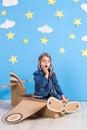 Little child girl in a pilot`s costume is playing and dreaming of flying over the clouds. Royalty Free Stock Photo