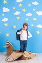 Little child girl in a pilot`s costume is playing and dreaming of flying over the clouds. Royalty Free Stock Photo