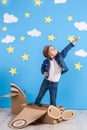 Little child girl in a pilot`s costume is playing and dreaming of flying over the clouds. Royalty Free Stock Photo