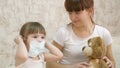 Little child girl quarantine, puts a medical mask on toy bear. protection against coronavirus and influenza. baby plays