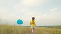 little child girl runs along rural road with blue balloon hands. happy childhood dream. rest kid outdoors park. picnic Royalty Free Stock Photo