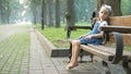 Little child girl sitting alone on a bench in summer park Royalty Free Stock Photo